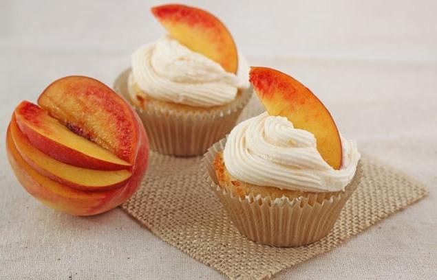 Deliziosi cupcakes pesca e zenzero con crema al burro di pesca su un piatto di legno