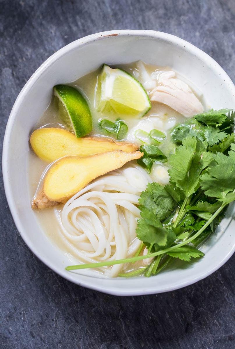 Zuppa di pollo asiatica con zenzero, coriandolo e noodles di riso. Una ciotola fumante e invitante.