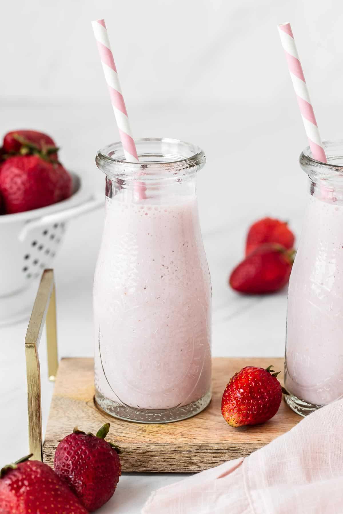 Latte alle fragole in un bicchiere con una cannuccia.