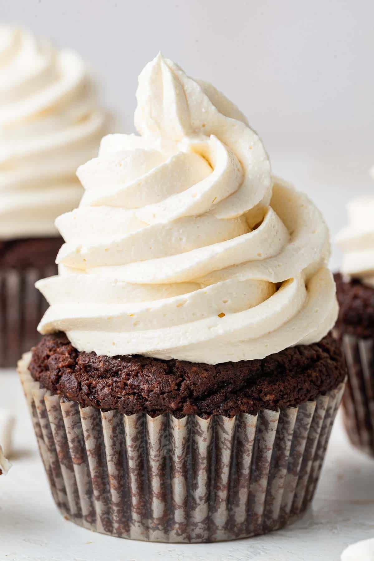 Close up photo of white swirled marshmallow frosting on a chocolate cupcake.