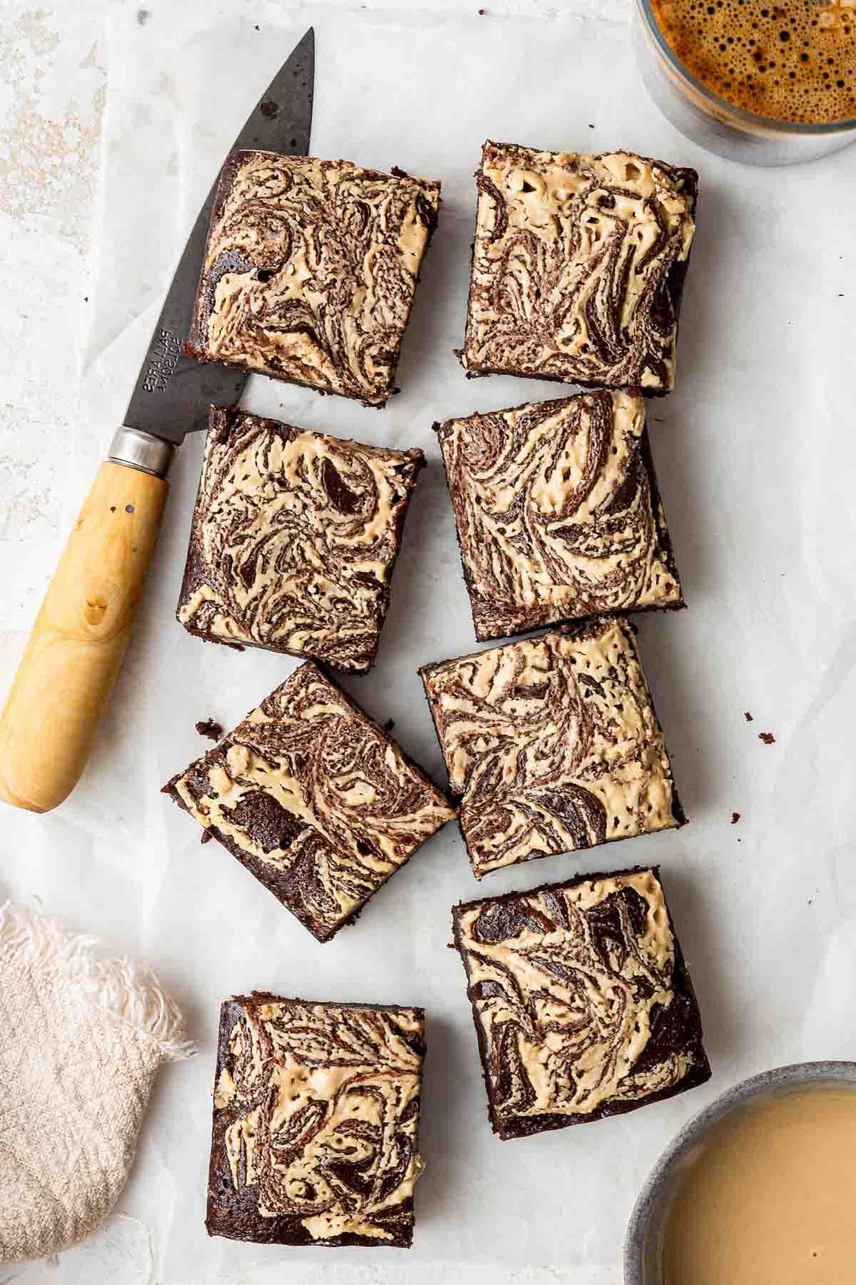 Vista dall'alto di brownies al tahini tagliati in otto piccoli quadrati con un coltello robusto.