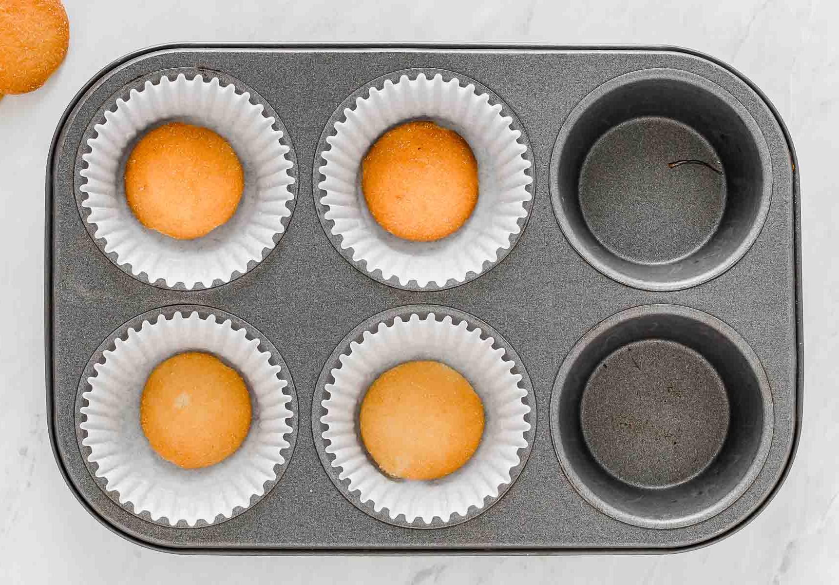 Quattro biscotti in pirottini per cupcake in una teglia.