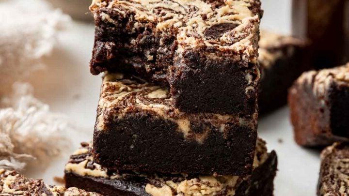 Pila di brownies al tahini con un morso mancante e caffè sullo sfondo.
