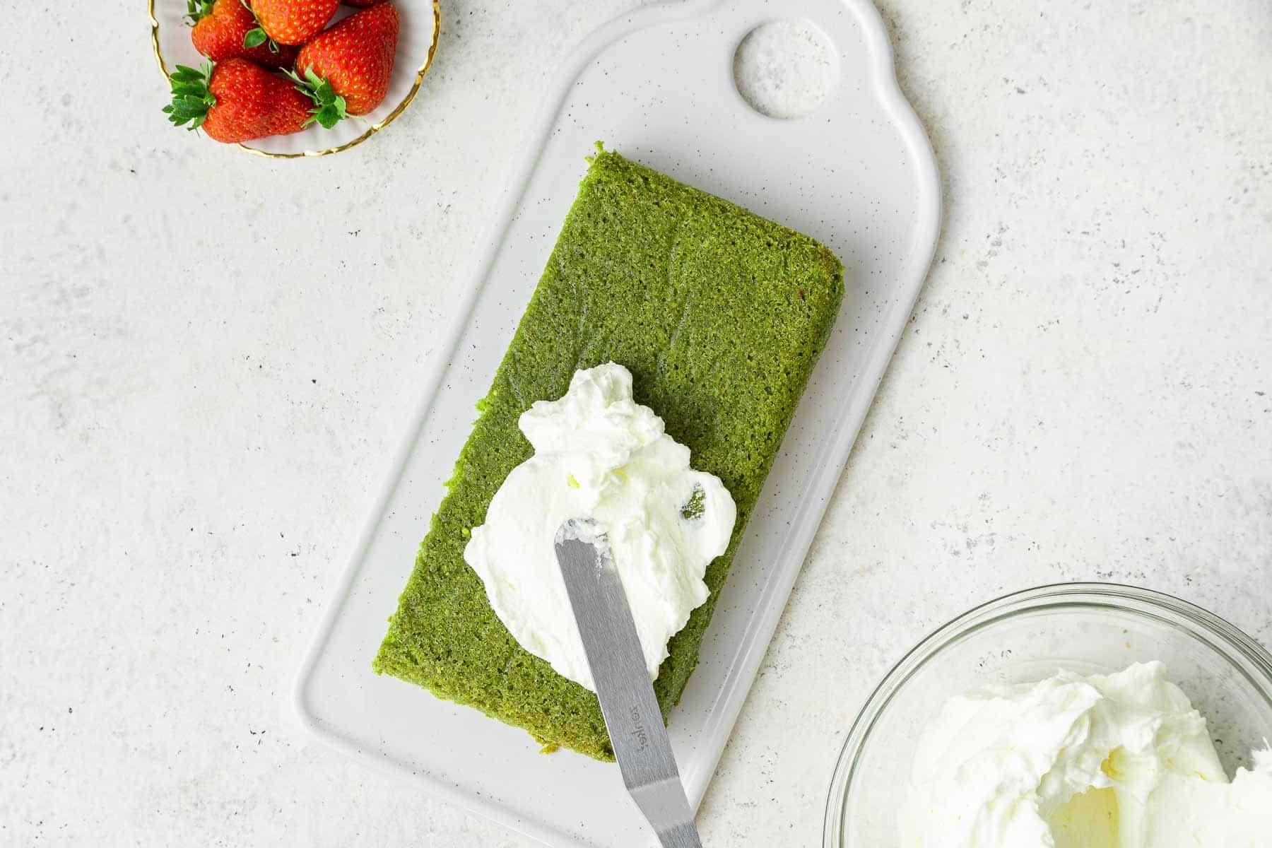 Torta al Matcha 12 Torta verde rettangolare spalmata con glassa bianca.