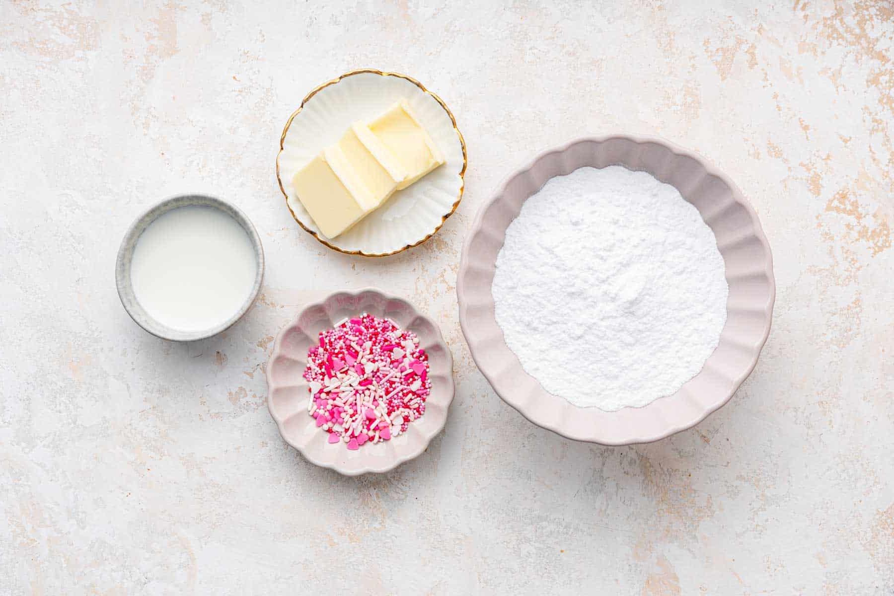 Four white bowls with butter, sugar and sprinkles.