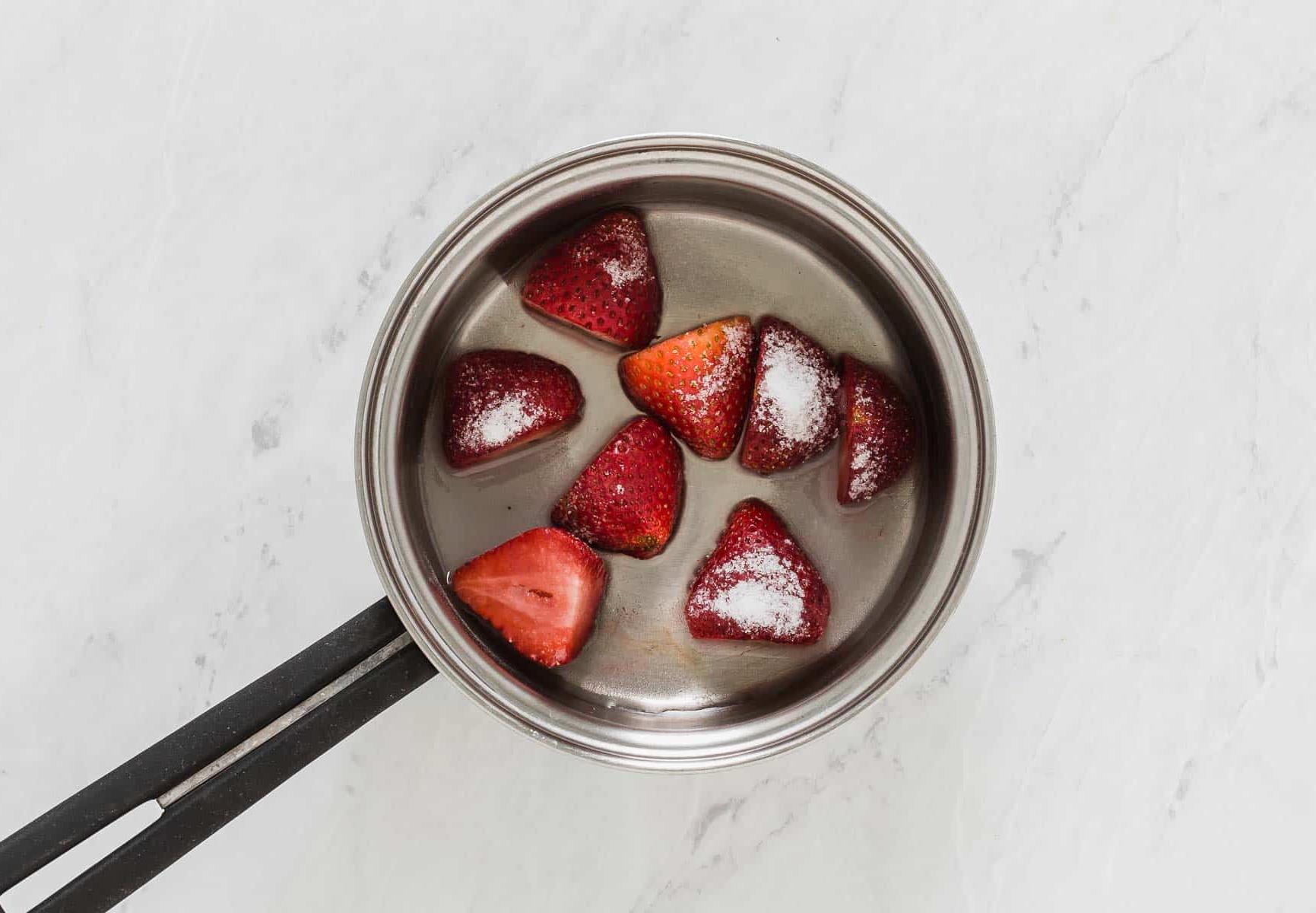 Fragole intere in una piccola casseruola.