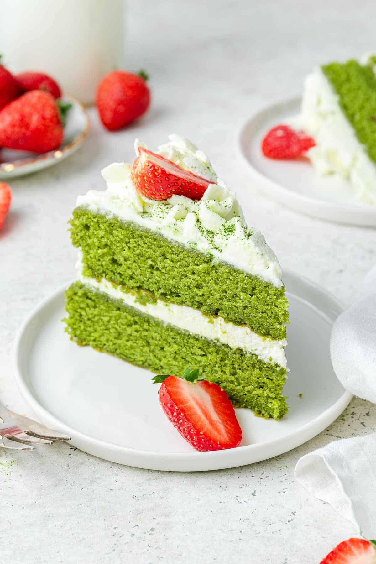 Torta al Matcha 14 Scatto ravvicinato di una torta al matcha con glassa bianca e fragole rosse fresche per guarnizione.
