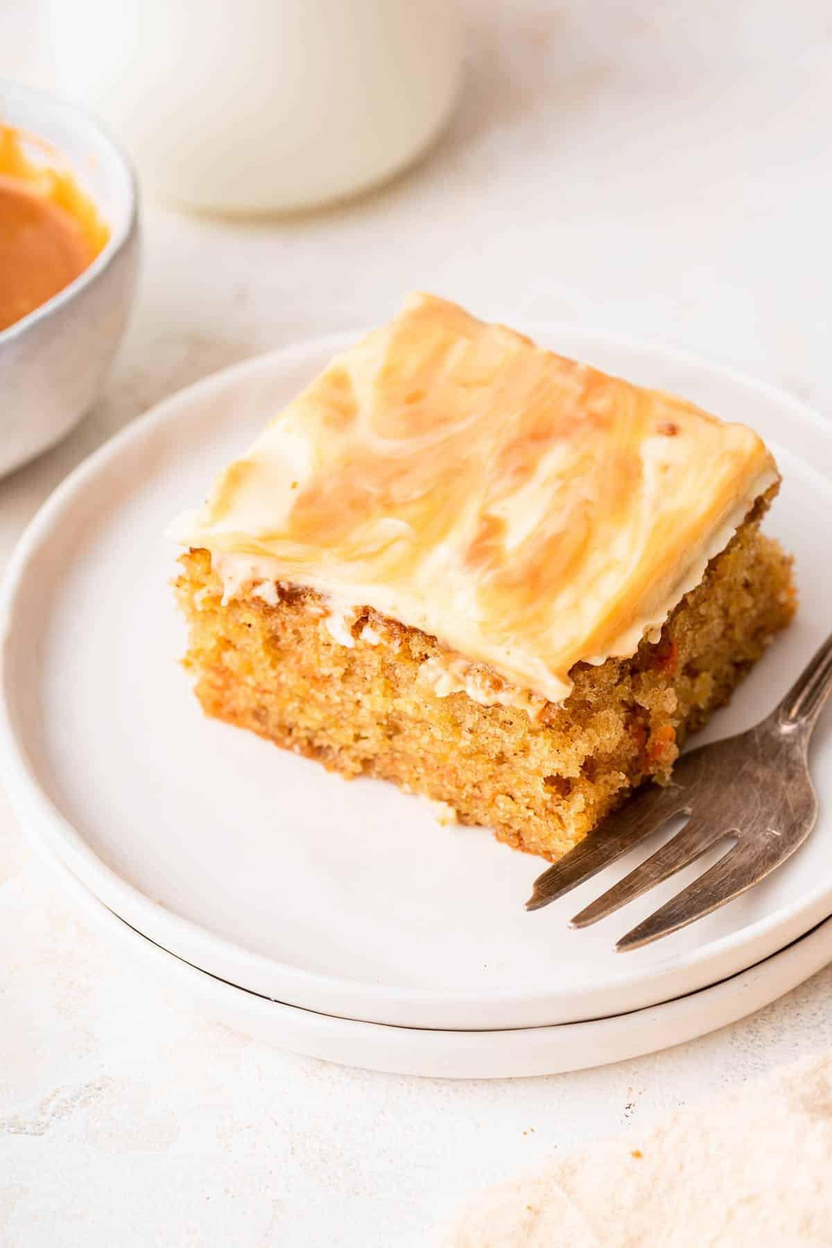 **Tortina di Carote con Glassa al Formaggio Cremoso al Caramello** 14 Fetta di torta di carote su piatto bianco con forchetta a lato, pronta per essere gustata.