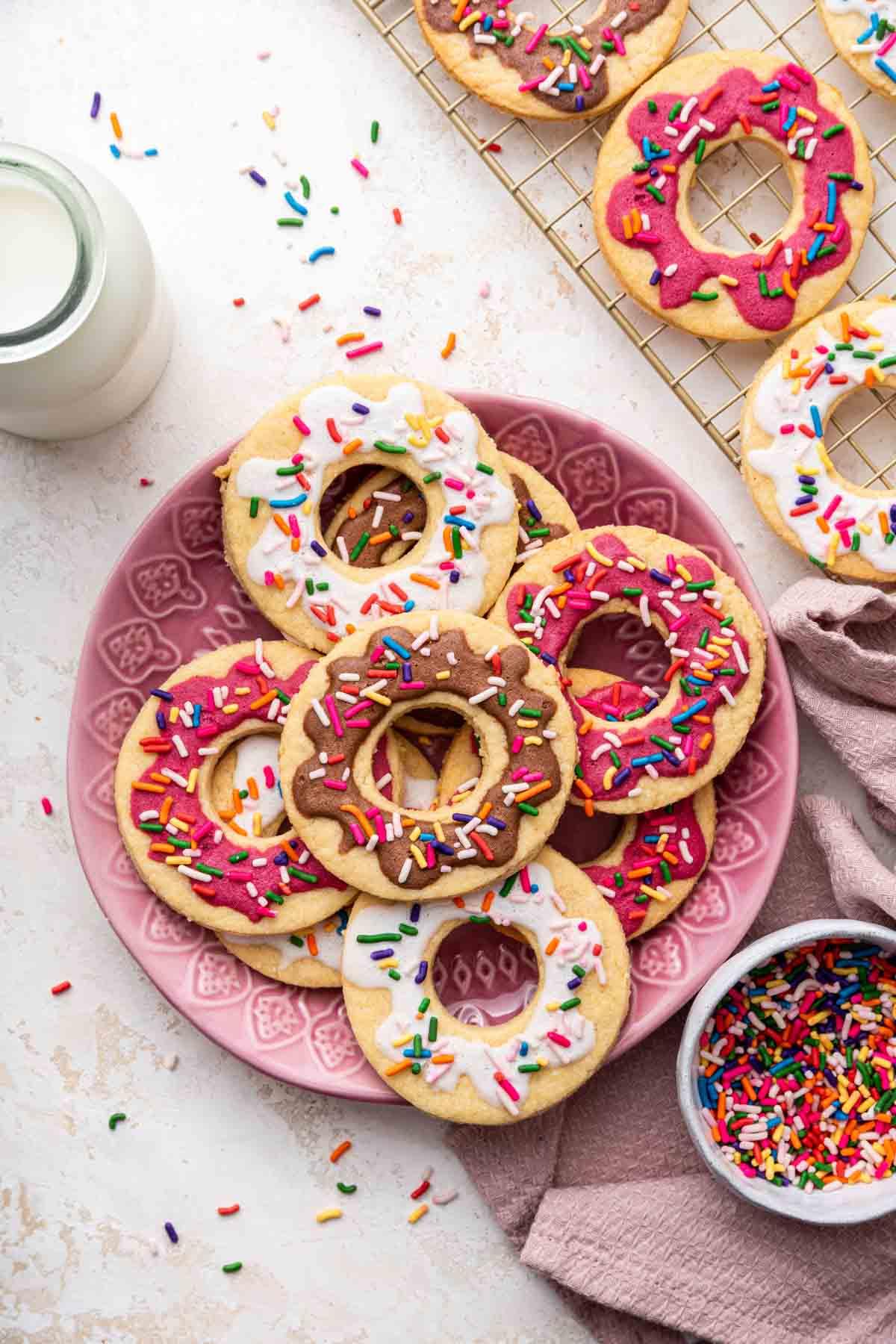 Biscotti Ciambella 14 Overhead shot of pink, white, and brown donut cookies on pink plate with sprinkles.
