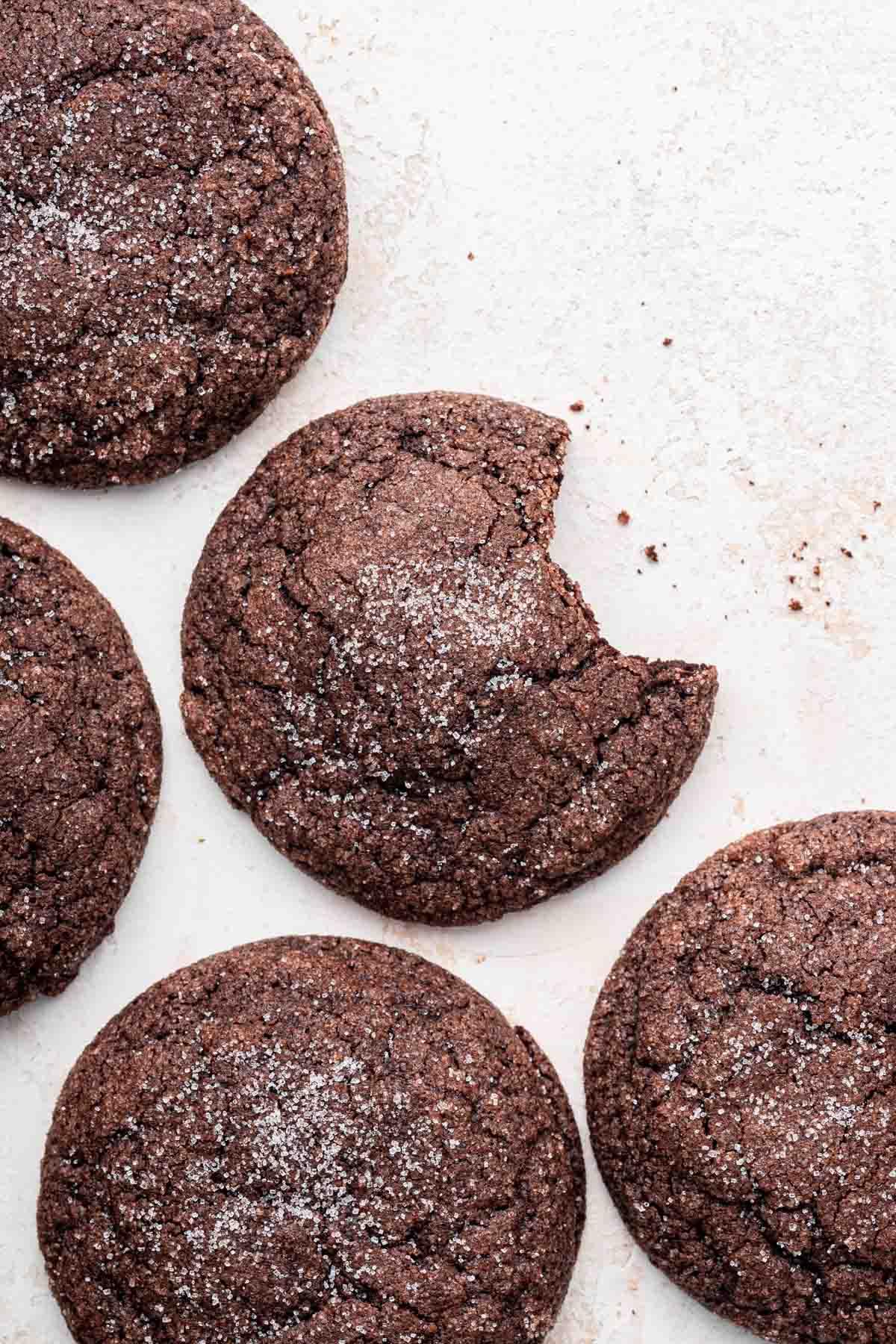 Overhead shot of five chocolate sugar cookies with one bite missing from the center cookie.