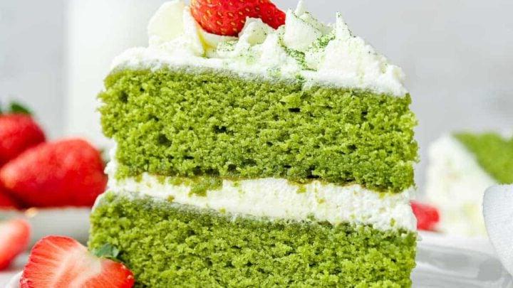 Torta al Matcha 15 Torta al Matcha di un verde brillante con glassa bianca e fragole fresche, scatto verticale ravvicinato.