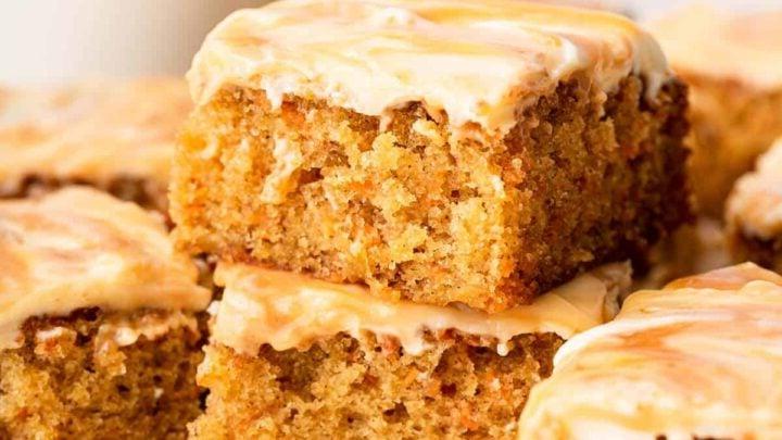 **Tortina di Carote con Glassa al Formaggio Cremoso al Caramello** 15 Due pezzi quadrati di torta di carote con glassa al caramello impilati, pronti per essere serviti.