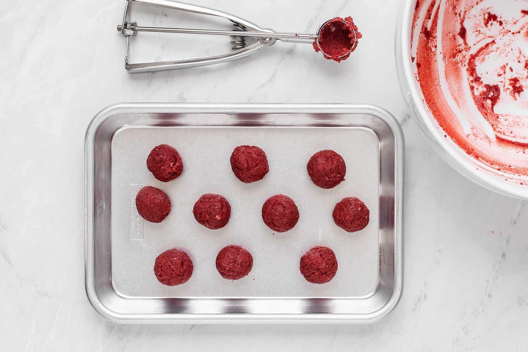 Dieci cake pops Red Velvet su una teglia per biscotti.