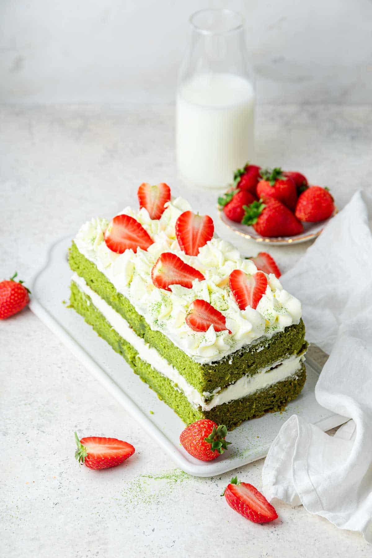 Torta al Matcha 3 Una torta a strati ricavata da una teglia per plumcake, decorata con glassa e fragole.