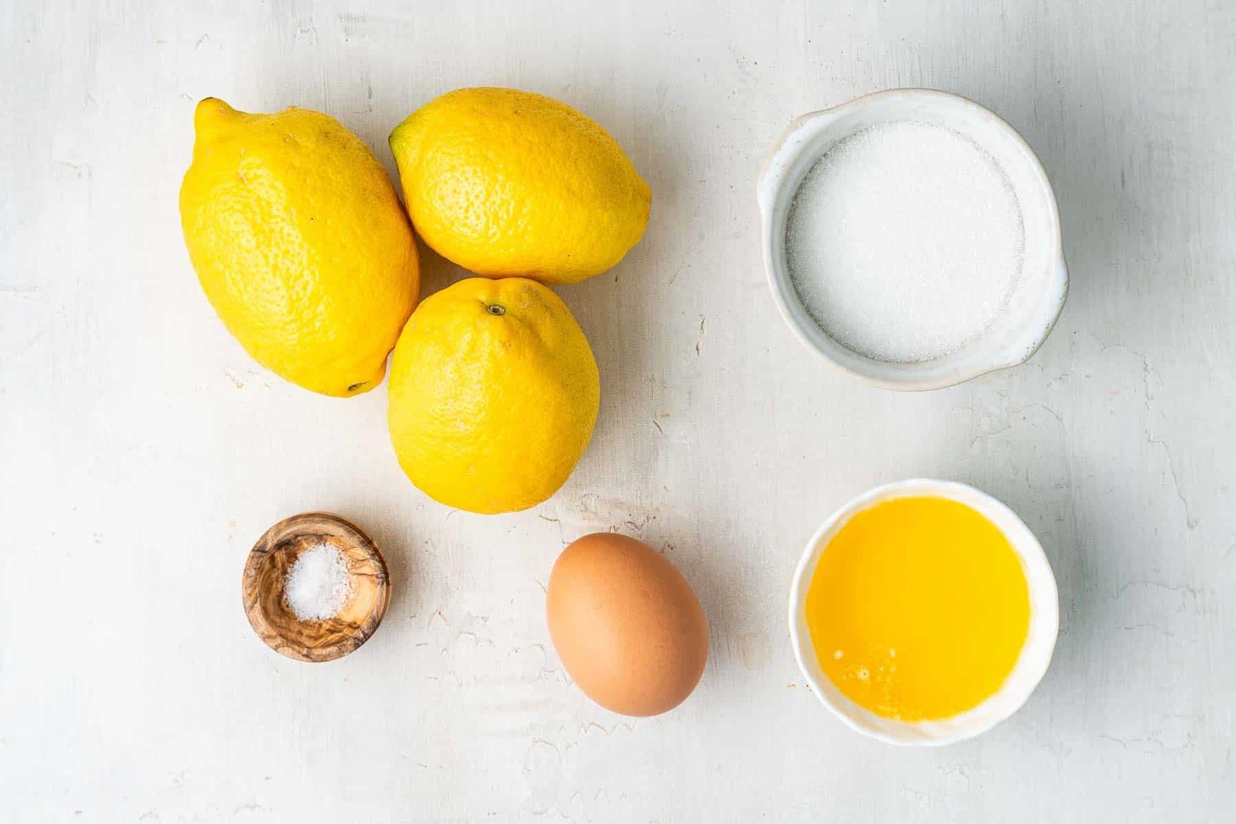 **Lemon Curd al Microonde in Piccola Quantità** 3 Tre limoni, uovo, burro e zucchero su un bancone di marmo.