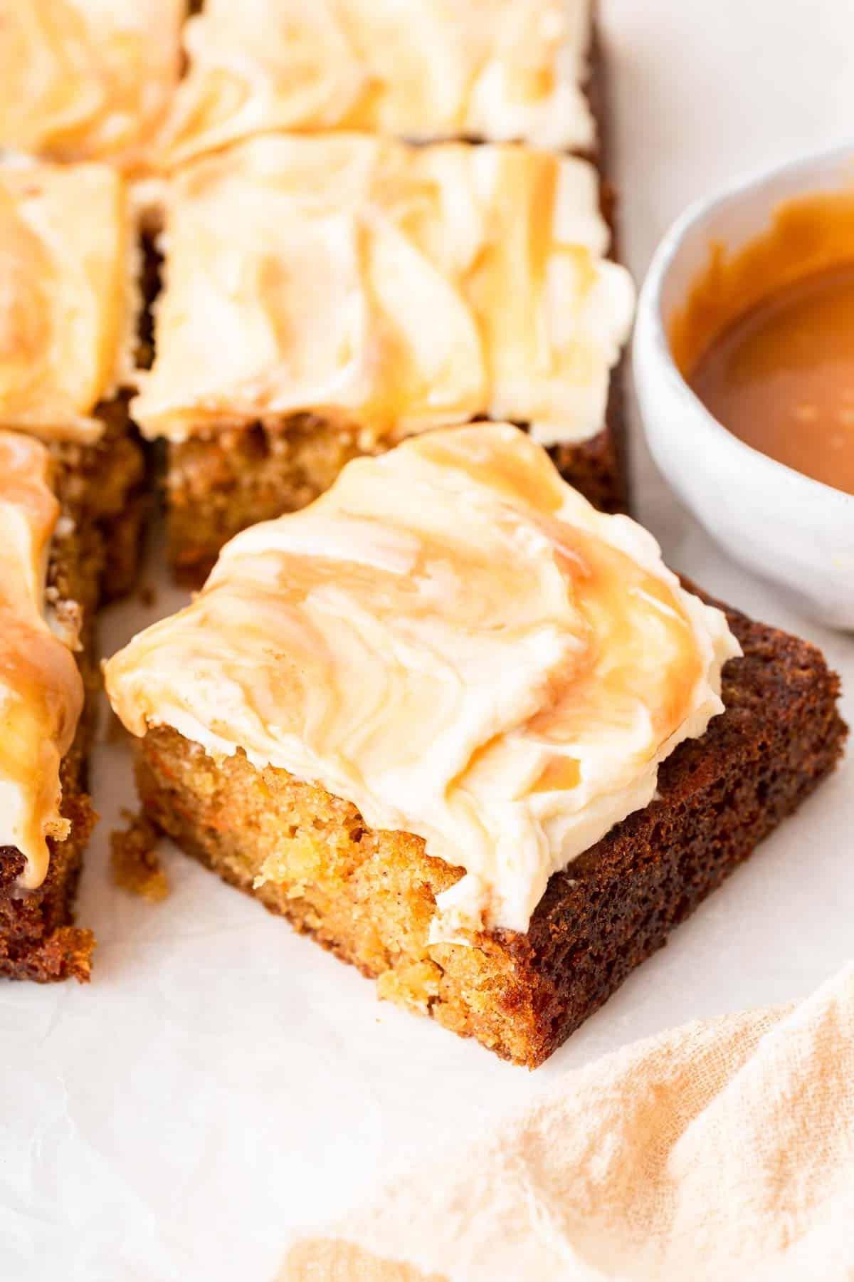 **Tortina di Carote con Glassa al Formaggio Cremoso al Caramello** 3 Un pezzo quadrato di torta di carote con glassa al caramello marmorizzata, che ne evidenzia la ricchezza.