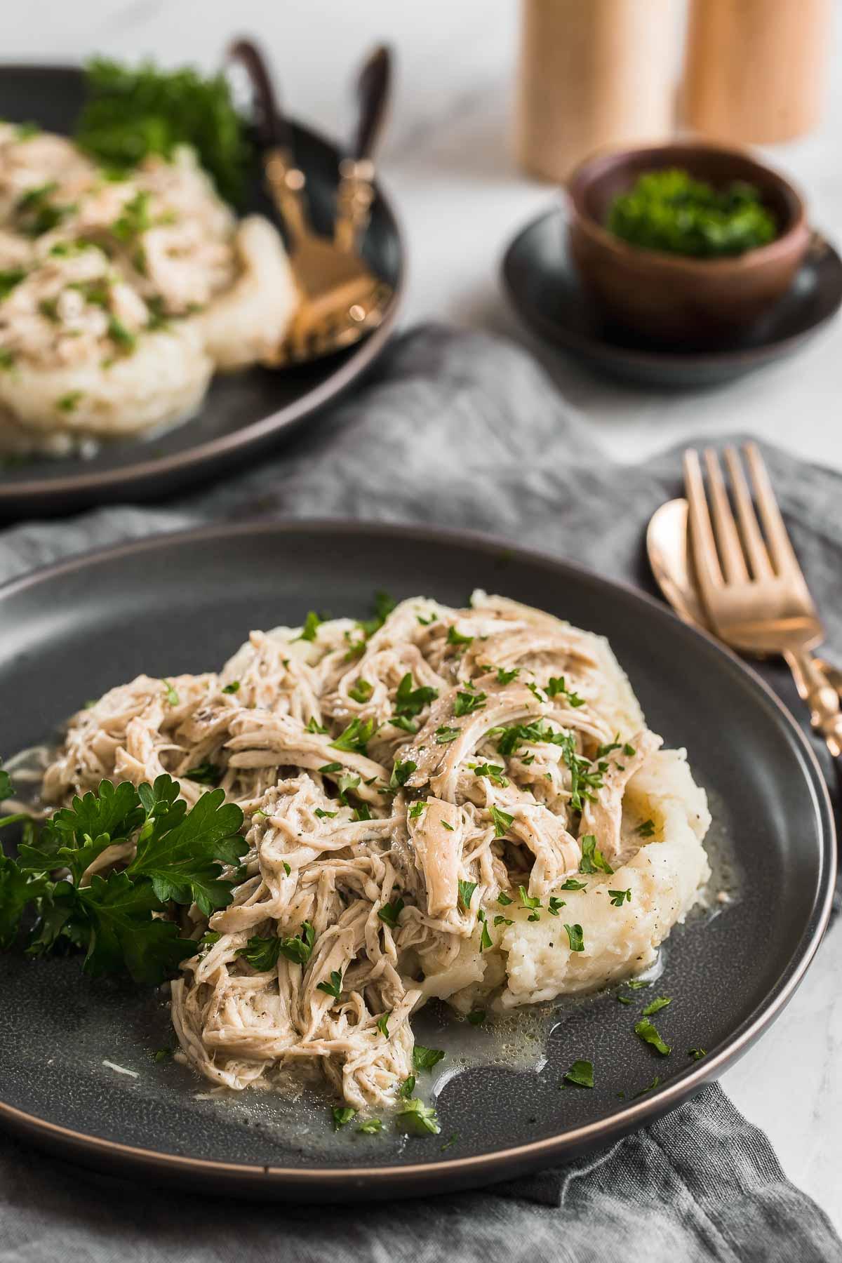 Pollo Cremoso in Pentola a Cottura Lenta 3 Due piatti di pollo sminuzzato su purè di patate.