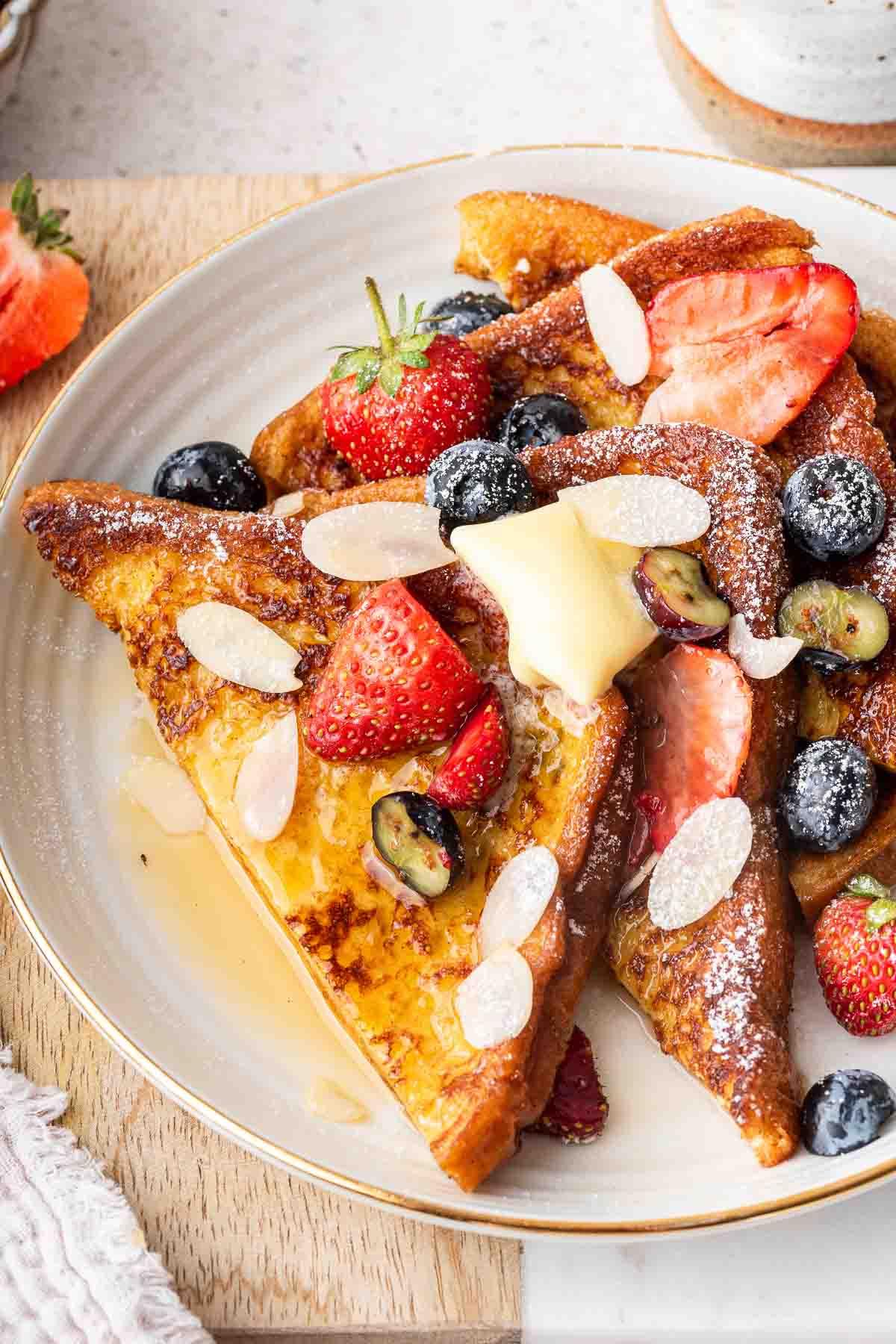 french-toast-for-two-recipe Primo piano macro di French toast di brioche ricoperto di frutti di bosco su un piatto.