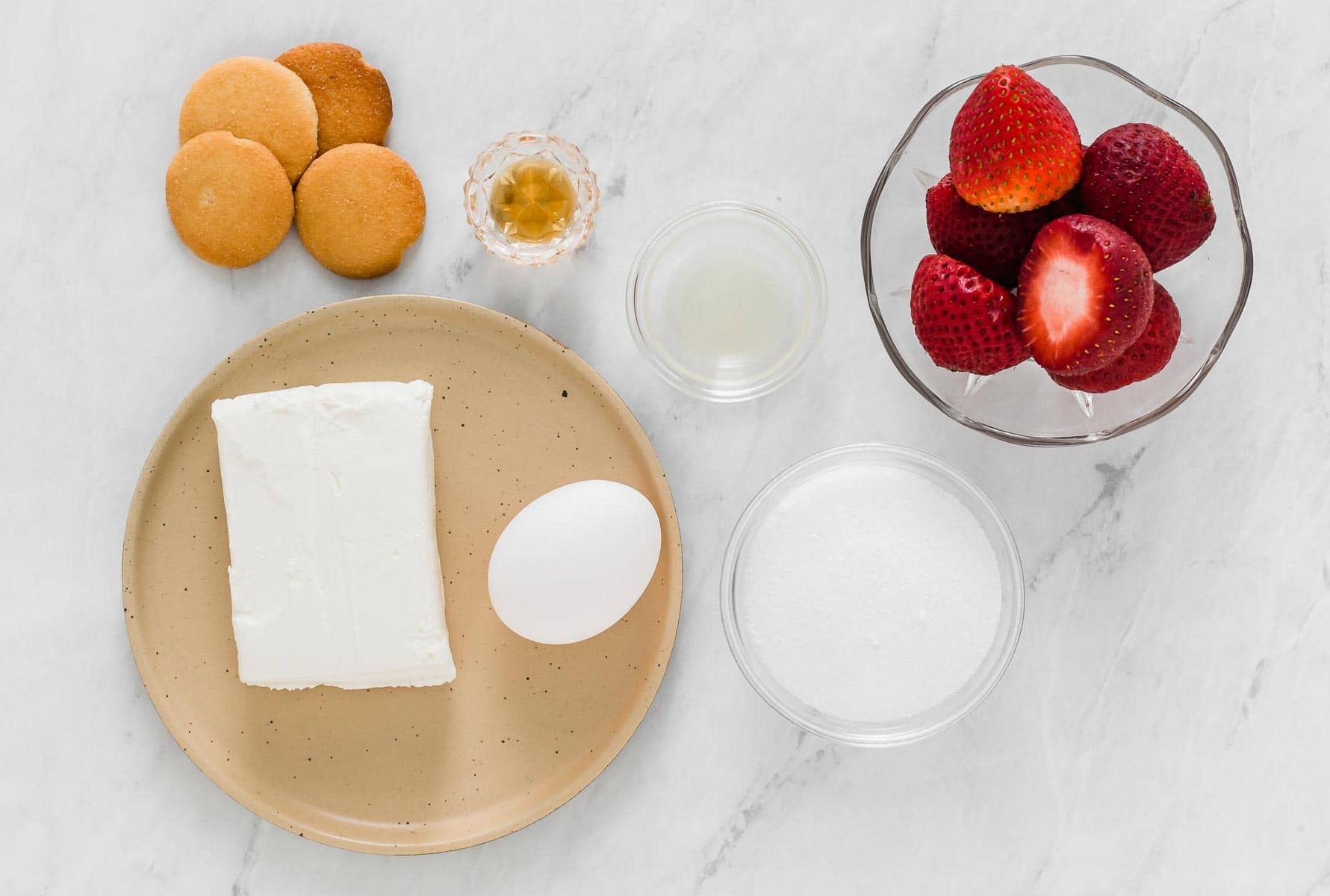 Ingredienti per mini cheesecake su un tavolo bianco.