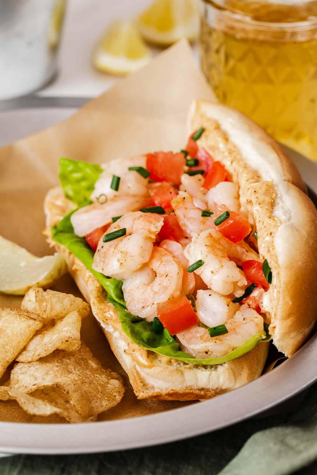 Panino Po' Boy di gamberi con pomodori e lattuga su un rotolo.