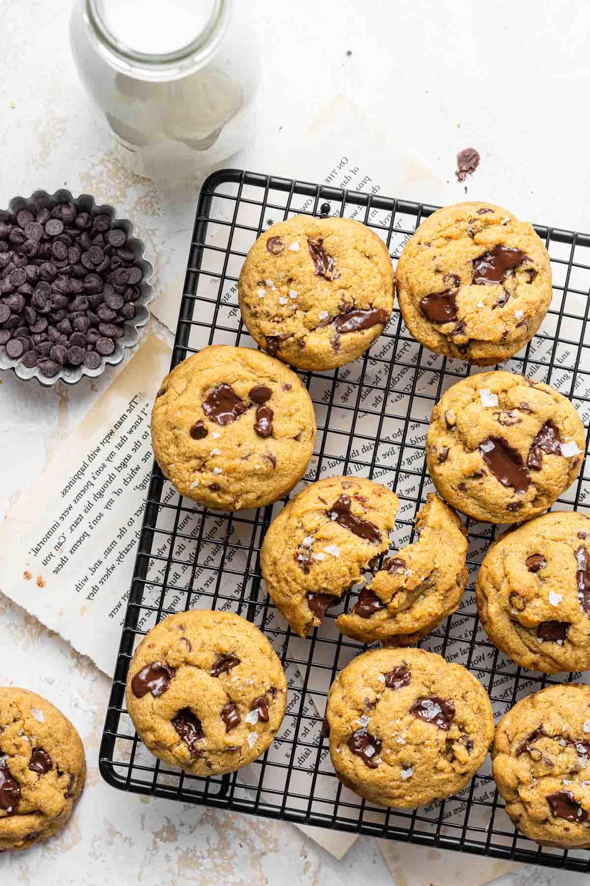 Biscotti su una griglia di raffreddamento con latte e gocce di cioccolato a lato.