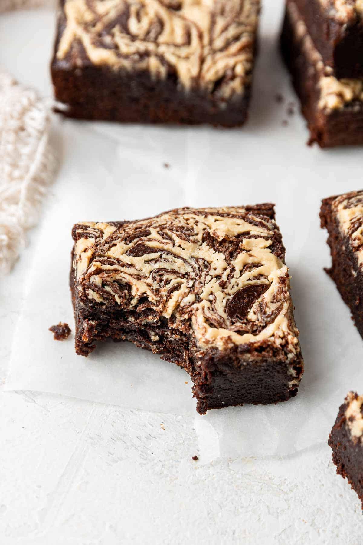 Brownie al tahini con morso mancante su carta forno bianca.
