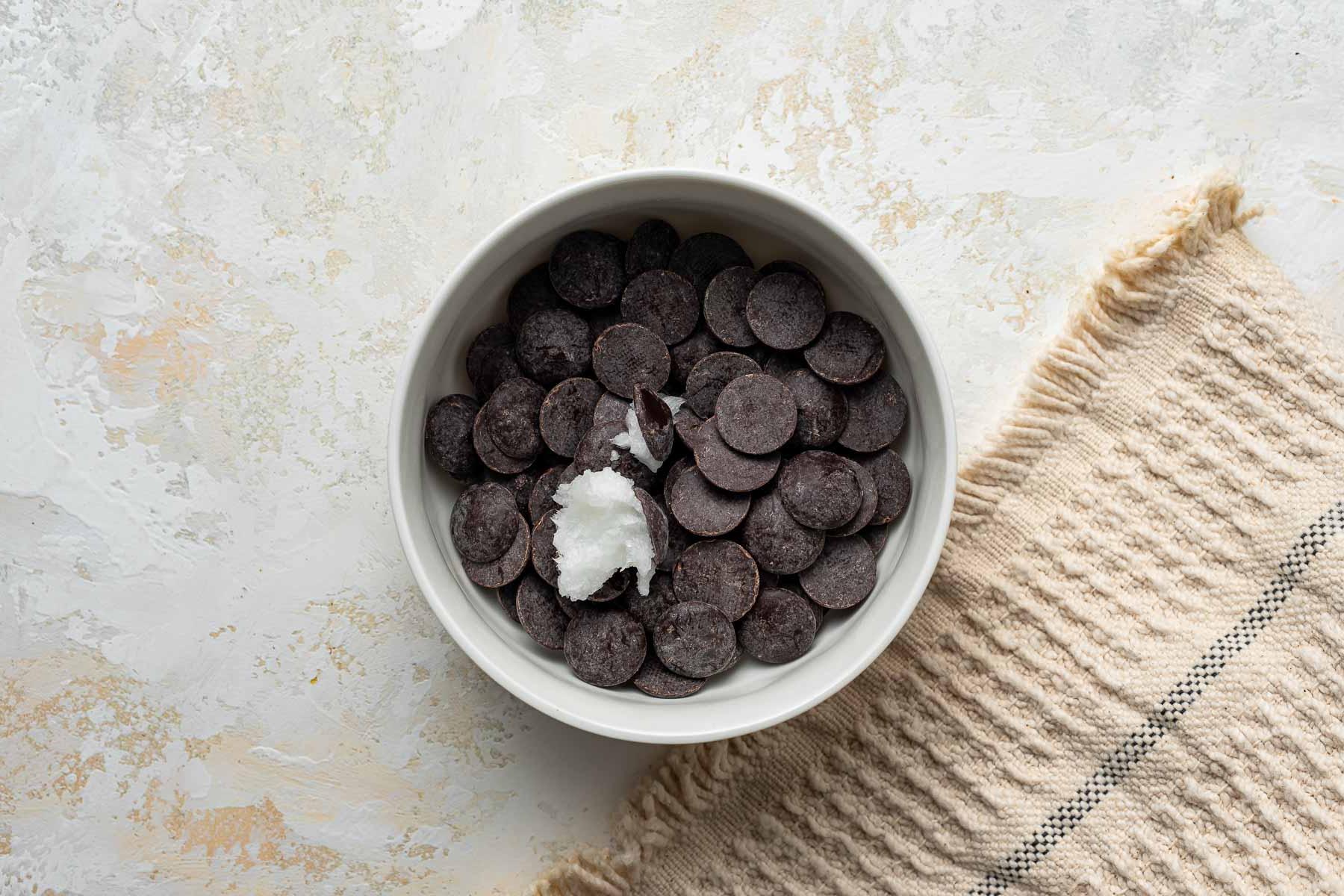 Gocce di cioccolato e olio di cocco in una piccola ciotola.