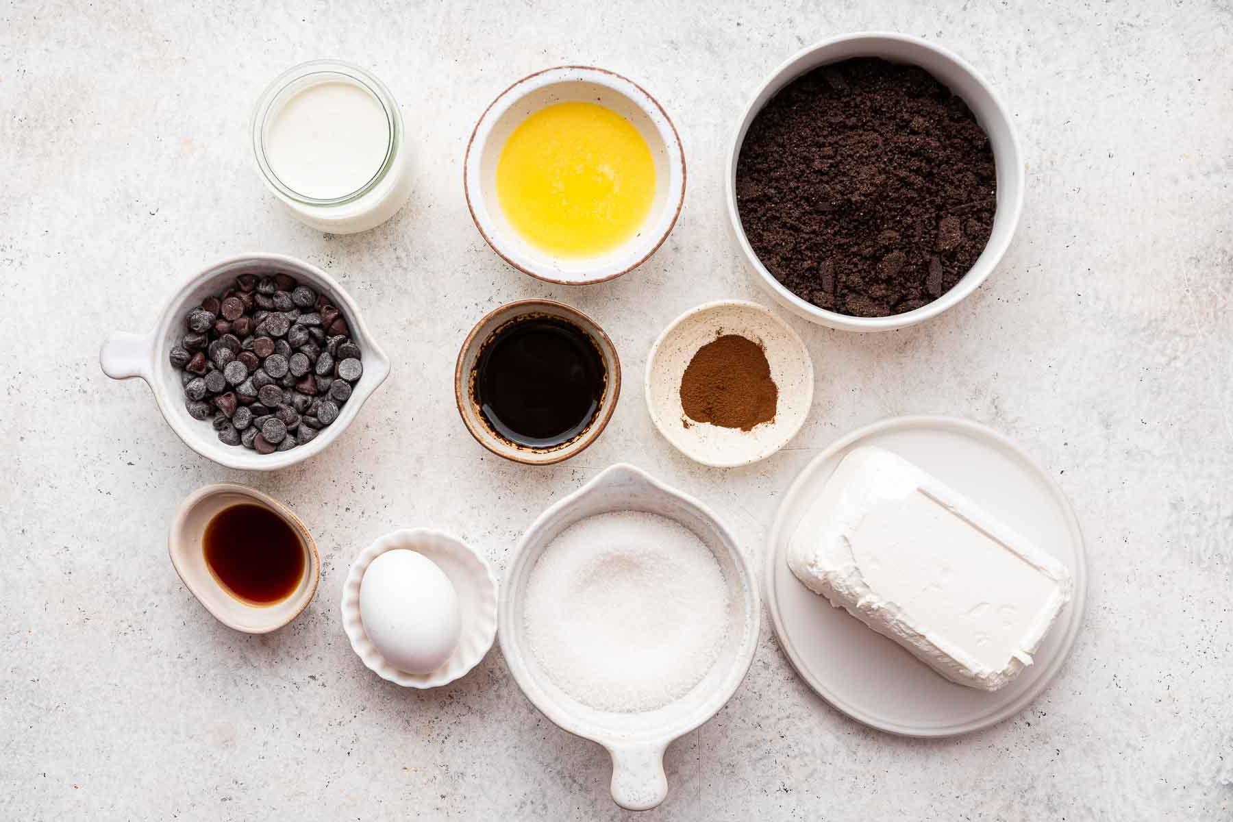 Cheesecake al caffè 4 Piccole ciotole di briciole di Oreo, burro fuso, formaggio cremoso e gocce di cioccolato, gli ingredienti principali per il cheesecake.
