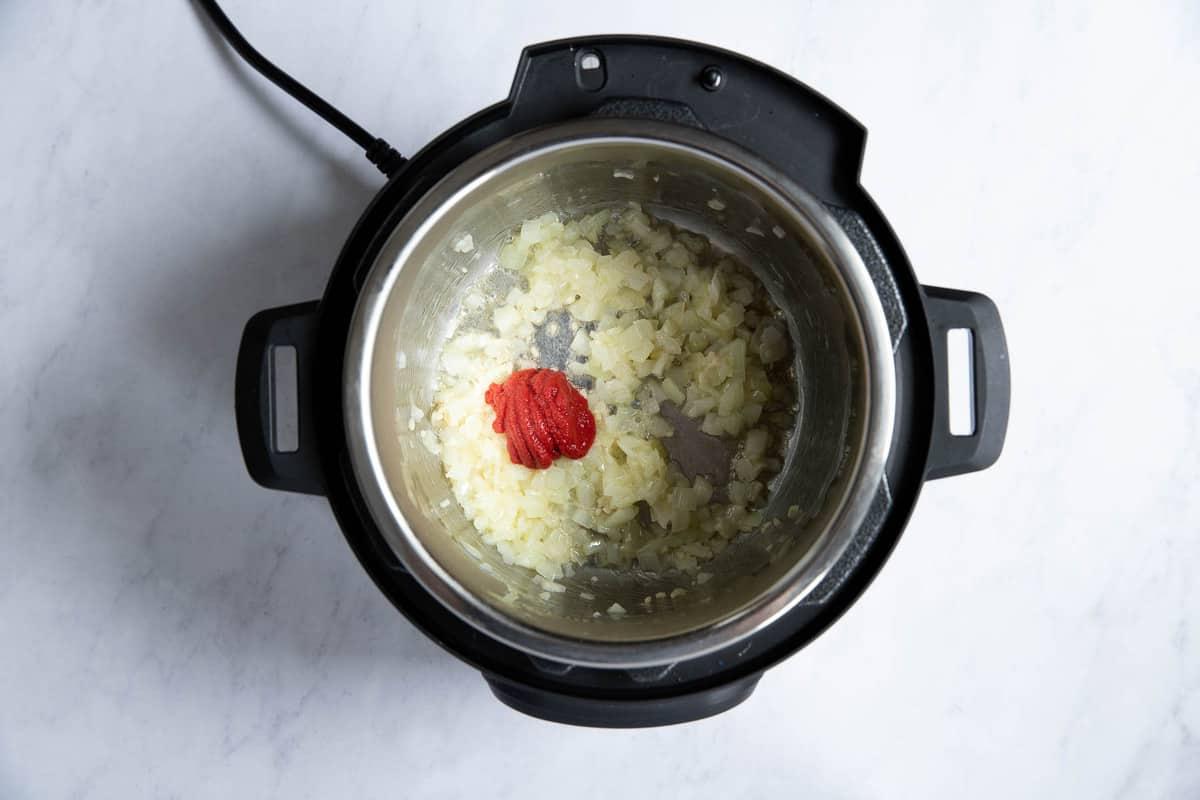 Concentrato di pomodoro con cipolle che cuociono nella Instant Pot.