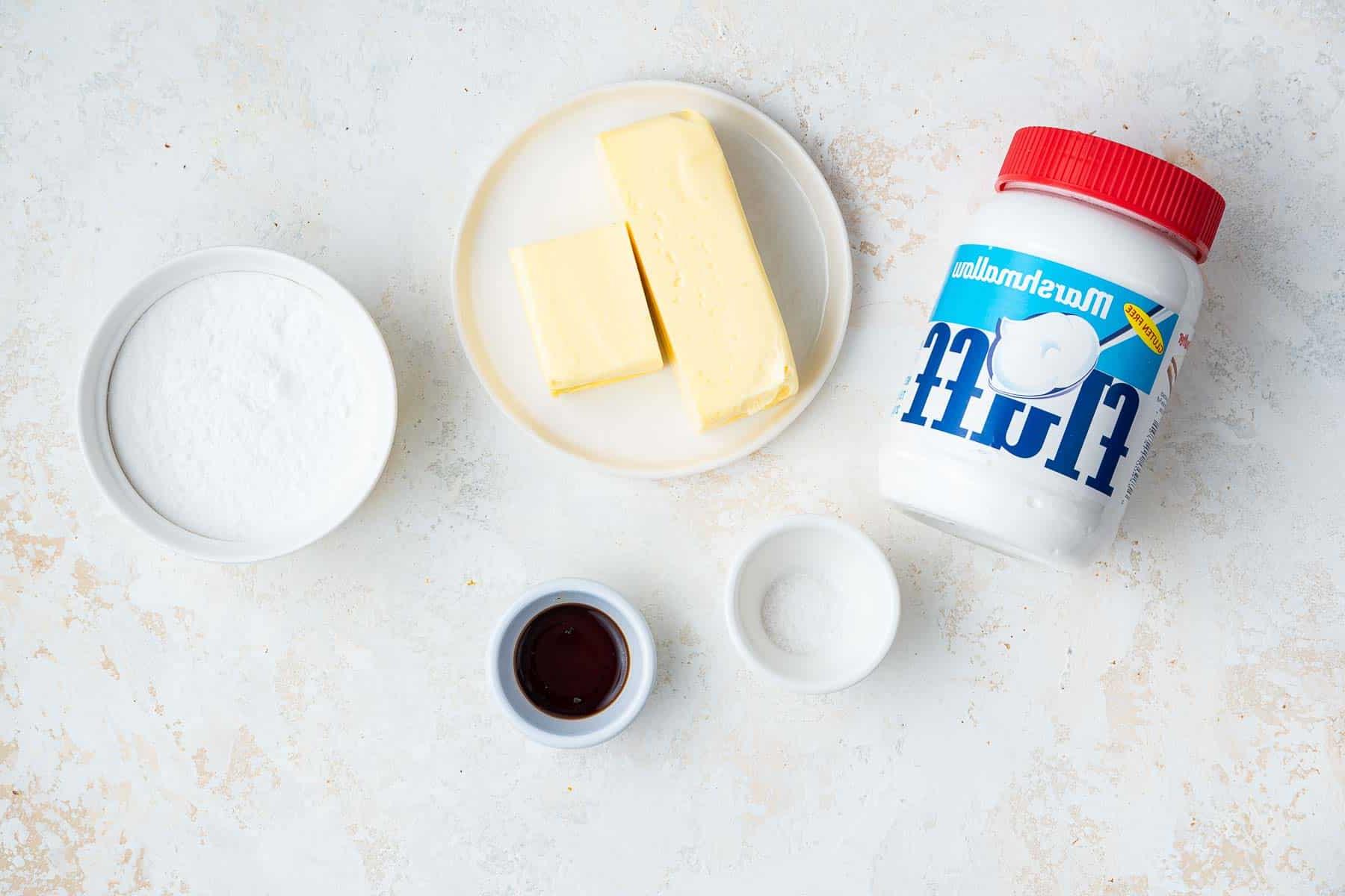 Photo of marshmallow fluff, butter, powdered sugar, salt and vanilla on grey counter.