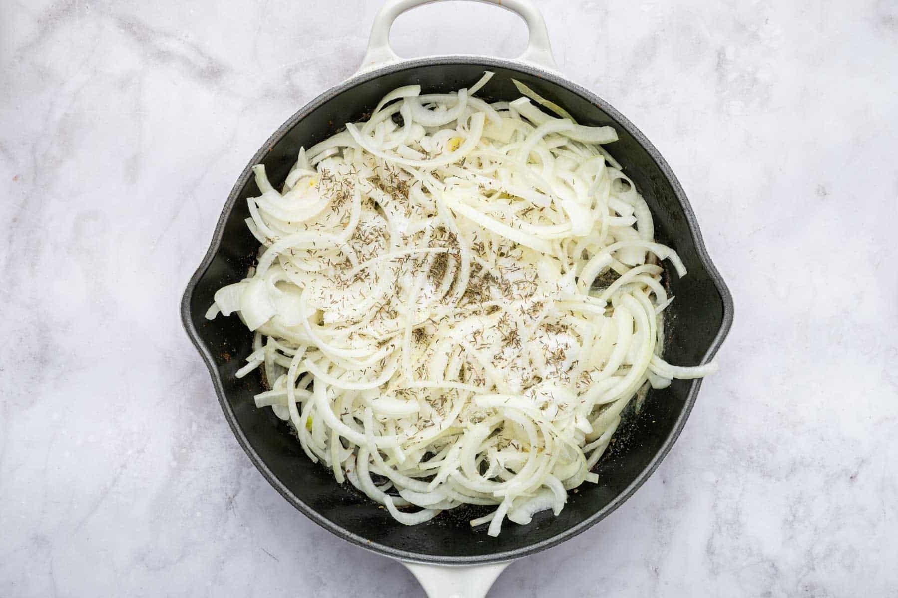 Ricetta del Pollo alla Cipolla Francese 5 Cipolle affettate sottilmente in una padella di ghisa, in fase di cottura.