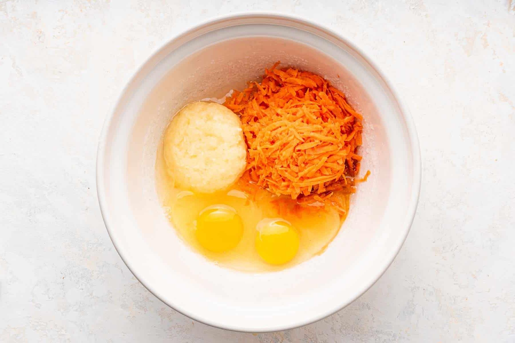 **Tortina di Carote con Glassa al Formaggio Cremoso al Caramello** 5 Ciotola bianca con carote grattugiate, ananas e uova, ingredienti freschi pronti per l'impasto.