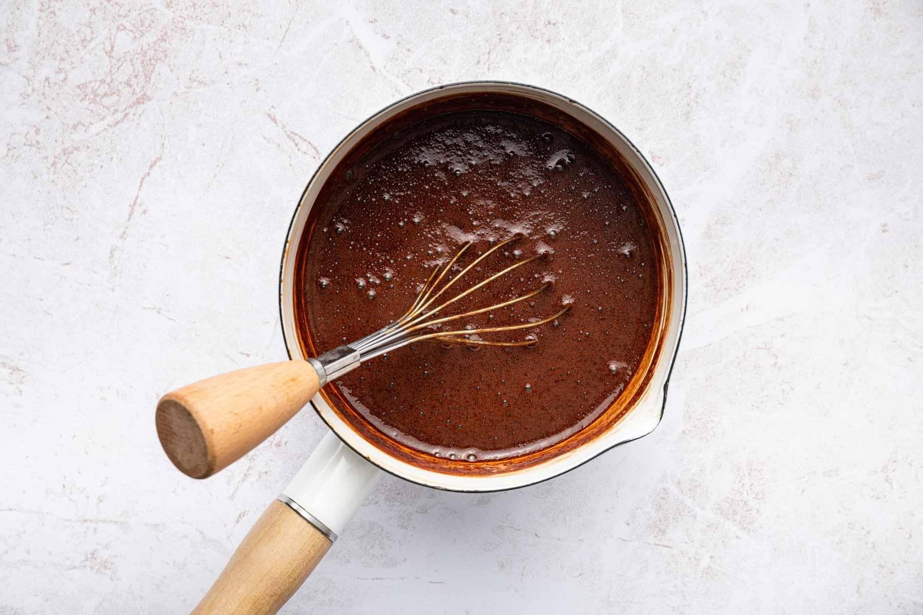 Ricetta Mocaccino Ghiacciato 5 Salsa marrone in una piccola padella bianca con frusta.