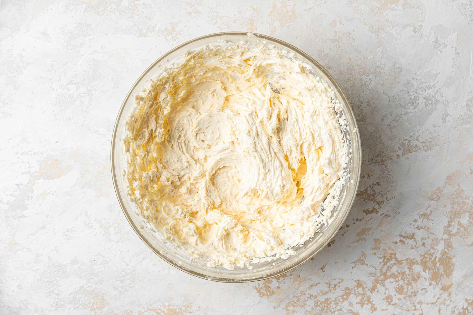 Crema al burro gialla in una ciotola di vetro trasparente.