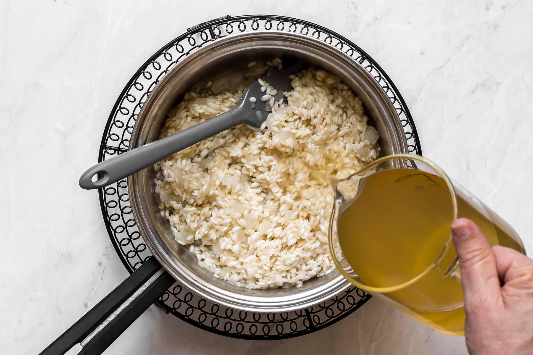 Brodo versato in una padella con riso.