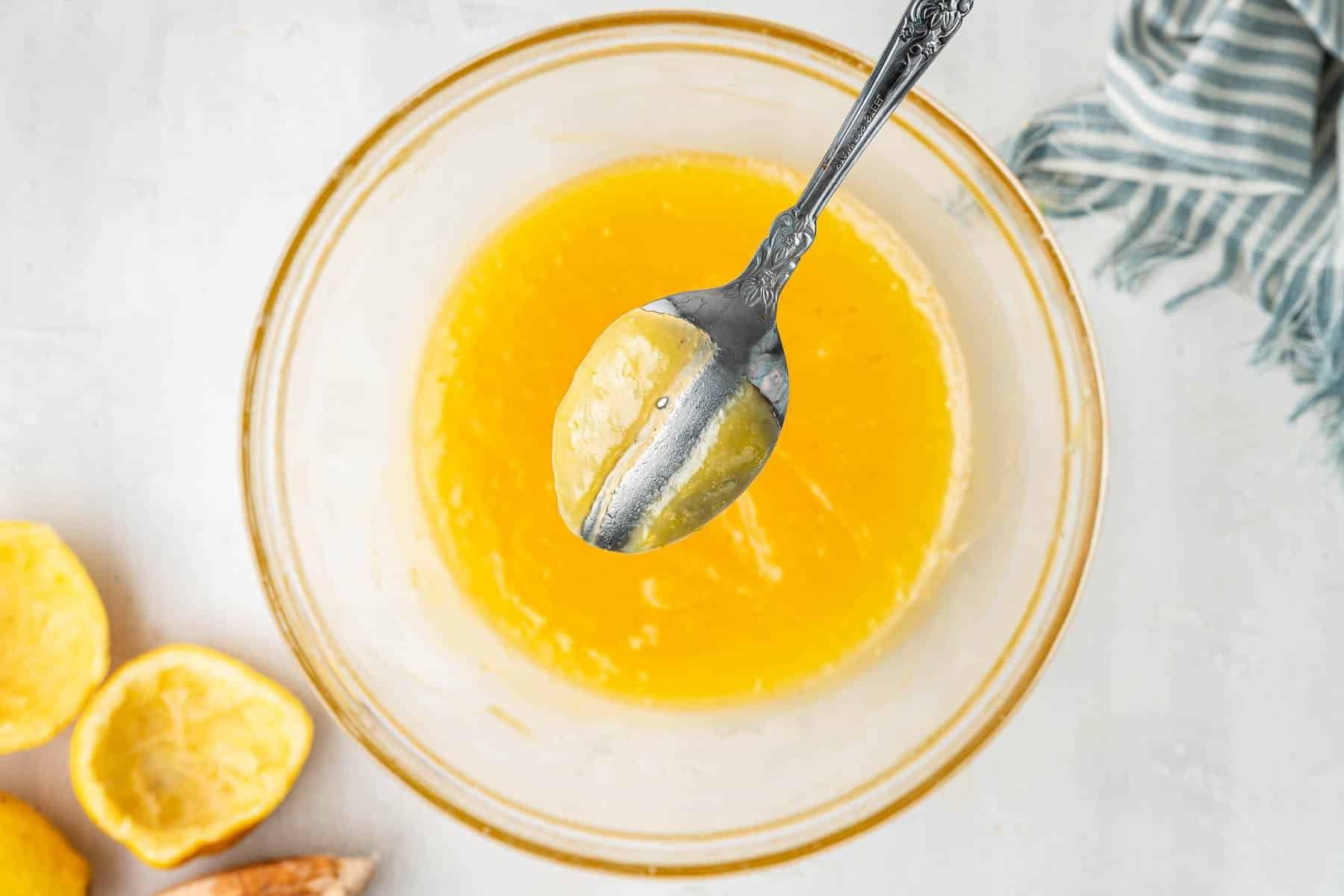 **Lemon Curd al Microonde in Piccola Quantità** 6 Cucchiaio di metallo immerso nella crema al limone al microonde con una striscia al centro.
