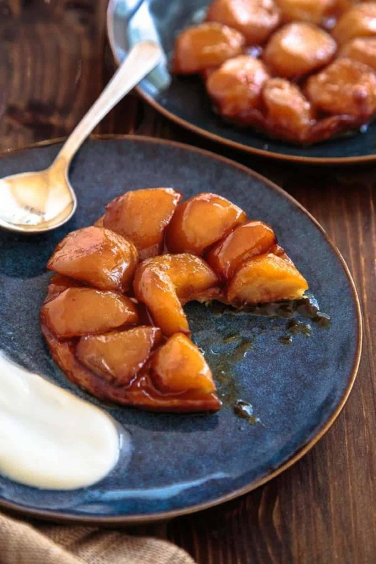 Il Giorno del Ringraziamento per Due 52 Due porzioni di tarte tatin di mele su piatti blu scuro con un ciuffo di panna, per un dessert elegante.