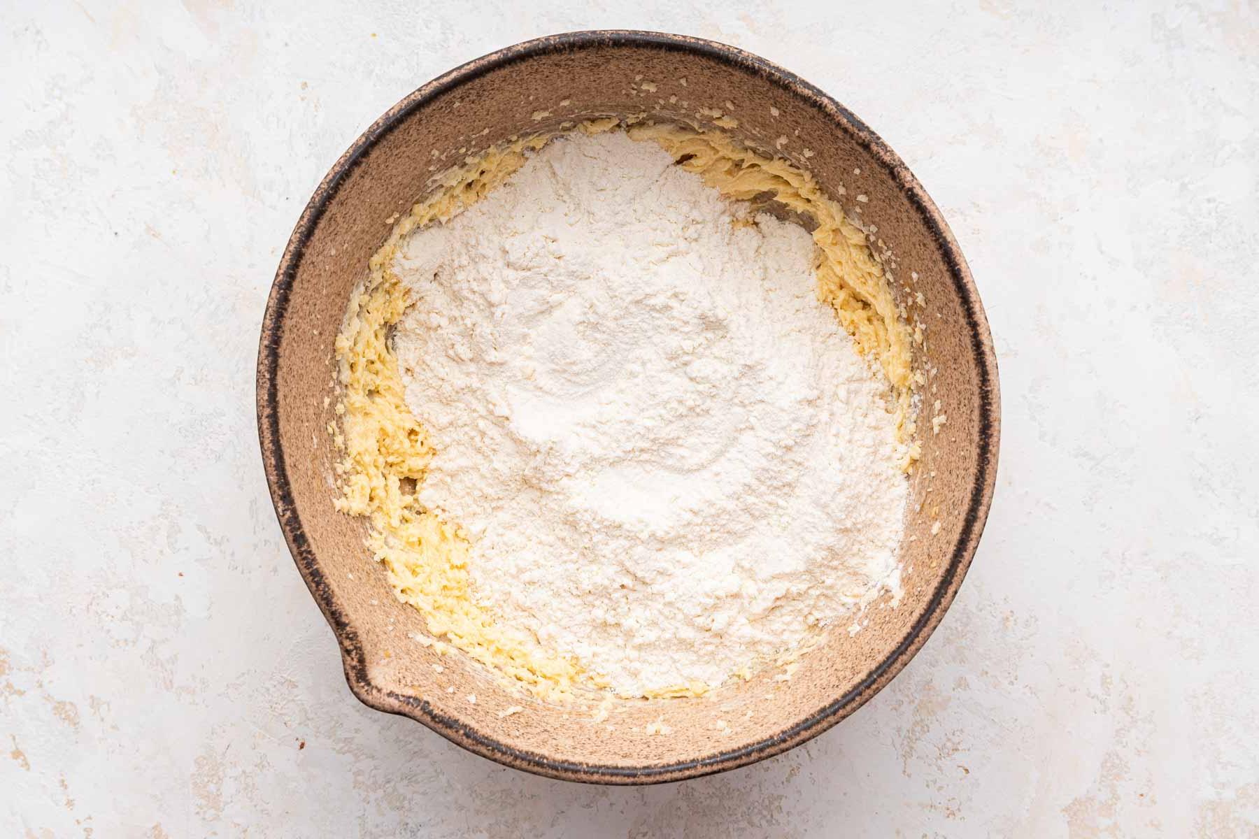 Biscotti Ciambella 7 Flour sprinkled over yellow cookie dough batter.
