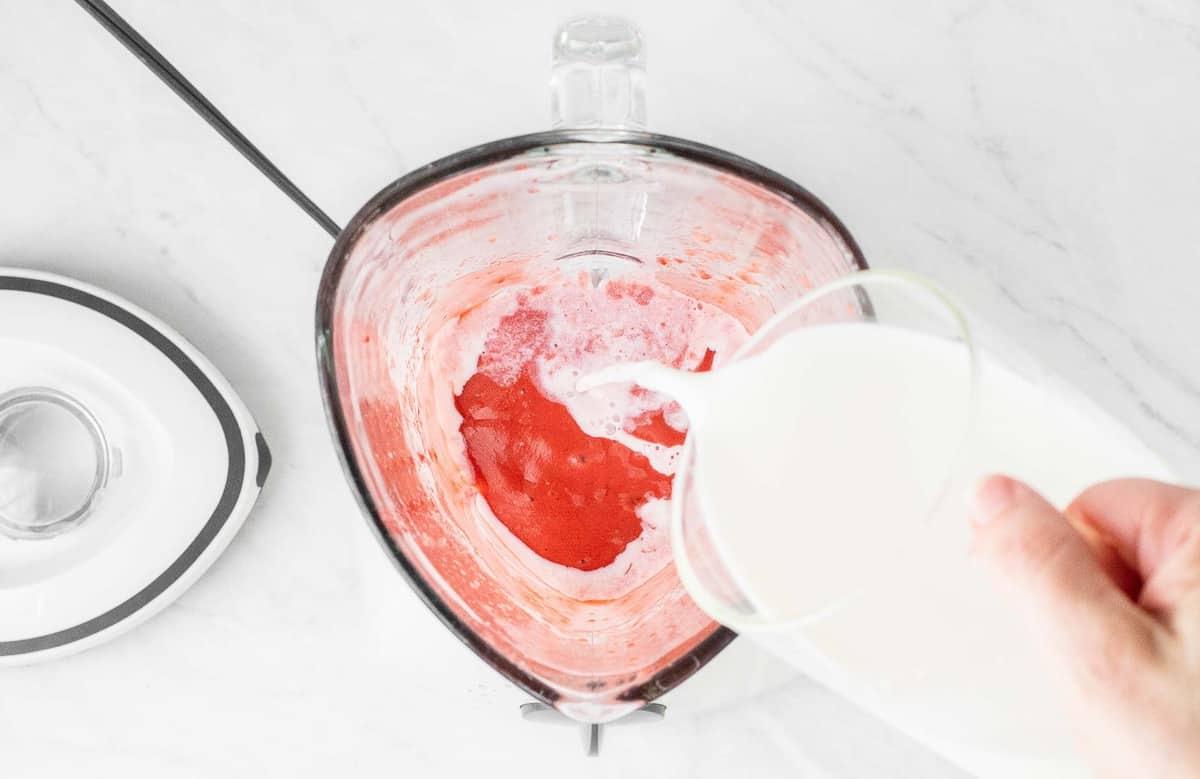 Versare il latte in un frullatore con le fragole.