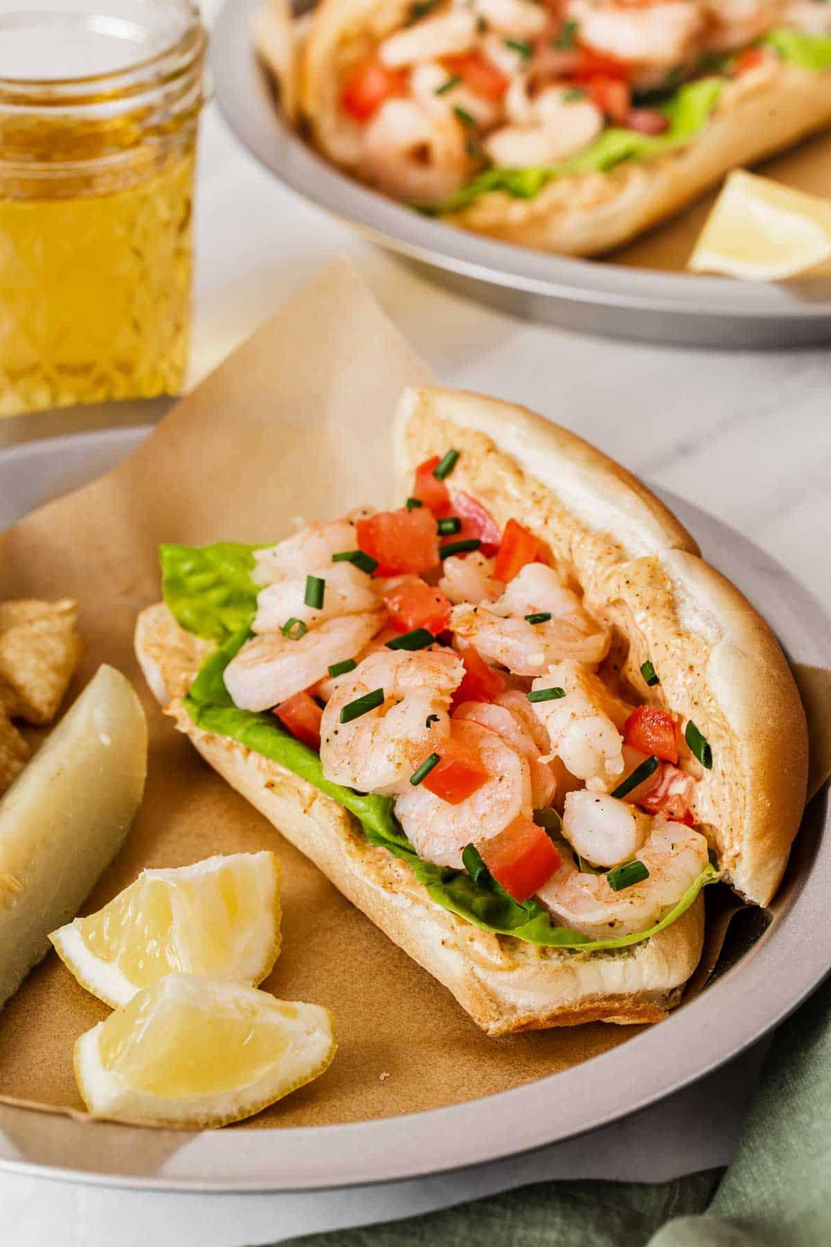 Panini freschi di gamberi serviti con spicchi di limone e un sottaceto.