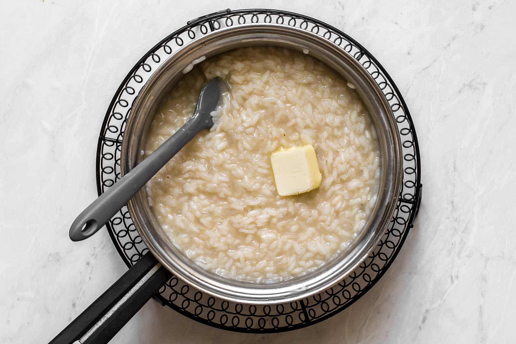 Burro che si scioglie in una pentola di risotto.