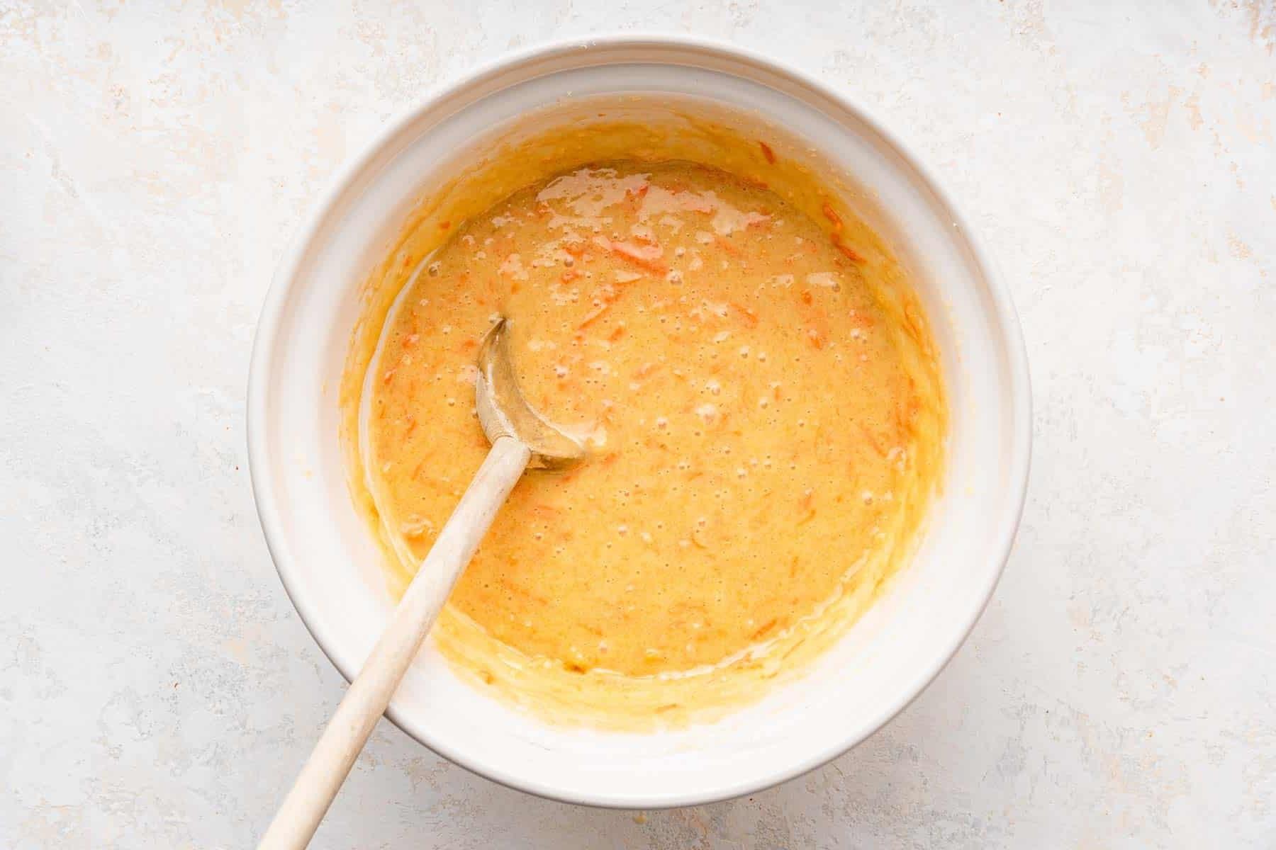 **Tortina di Carote con Glassa al Formaggio Cremoso al Caramello** 7 Ciotola bianca con impasto da giallo chiaro a arancione, una consistenza perfetta per la torta.