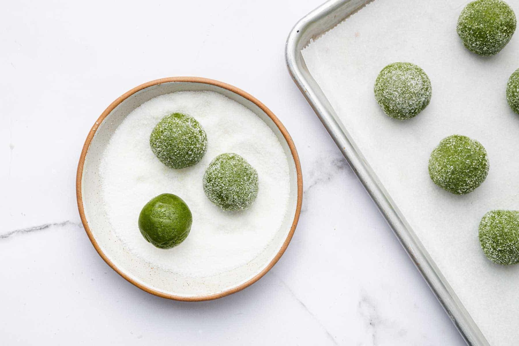 Biscotti al Tè Verde Matcha 8 Piccole palline di impasto verde vengono rotolate nello zucchero.