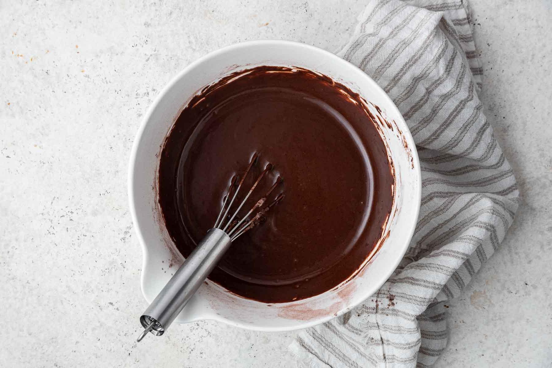 Ricetta Torta al Cioccolato in Tazza 8 Impasto marrone in una ciotola bianca con frusta.