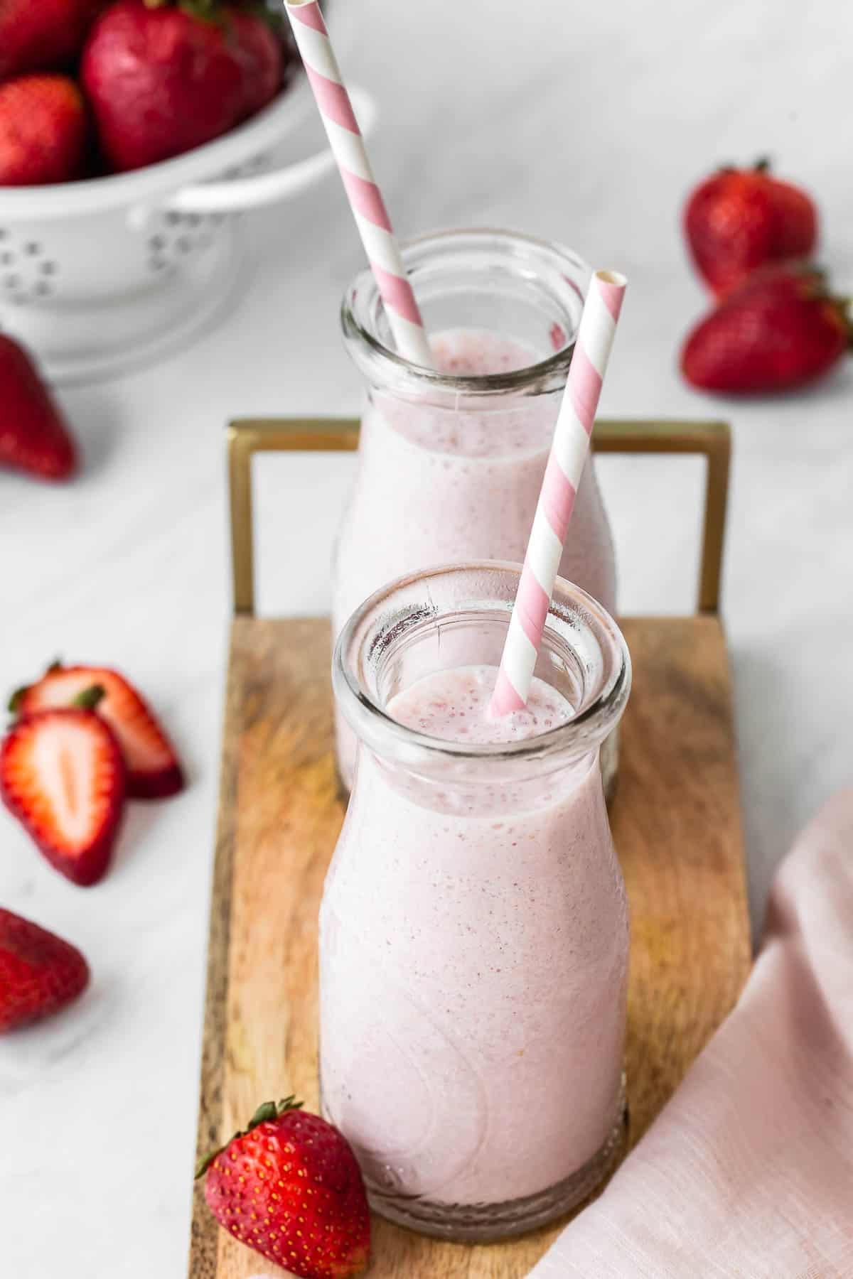 Due bicchieri di latte alle fragole con cannucce.