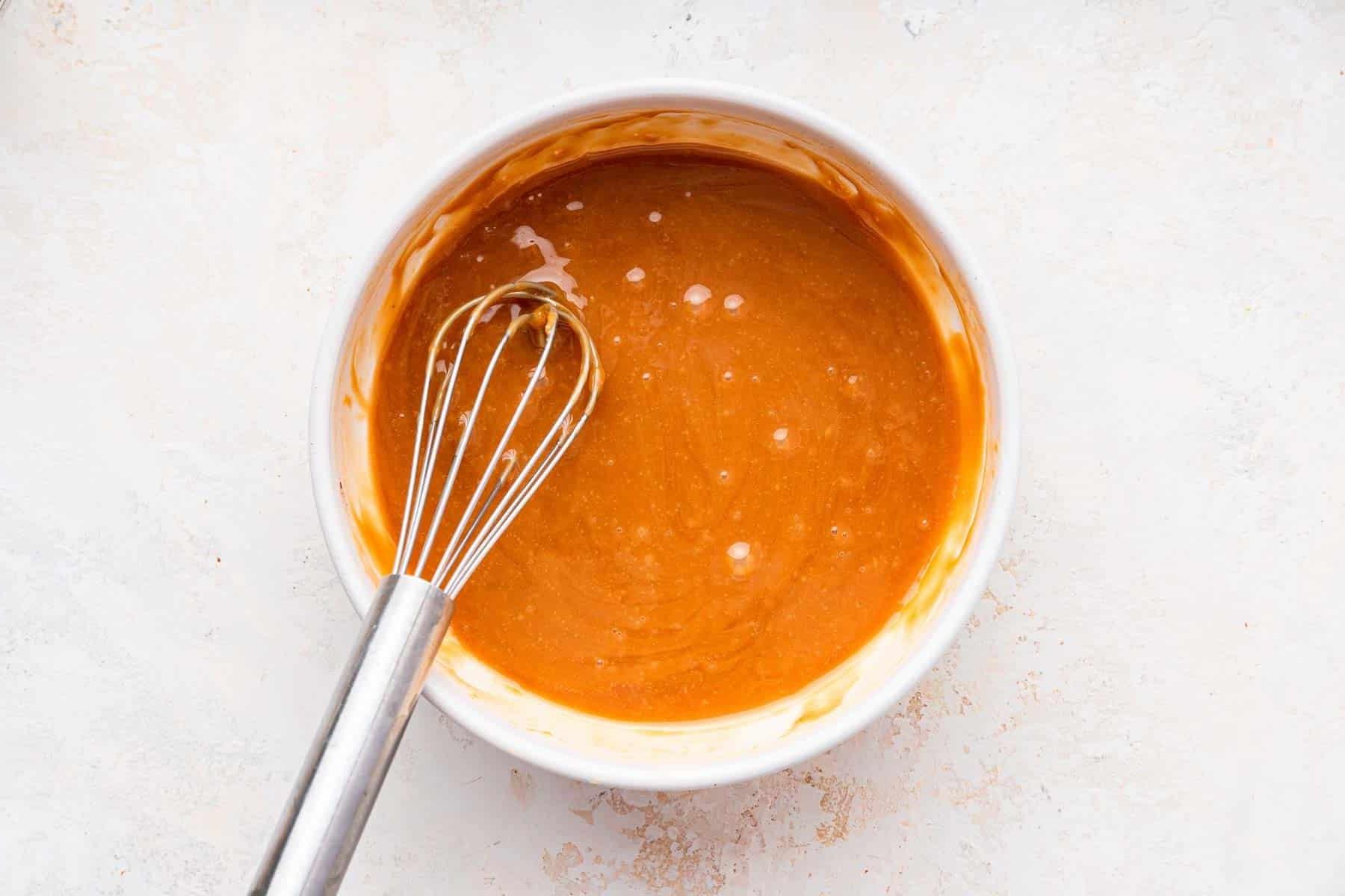 **Tortina di Carote con Glassa al Formaggio Cremoso al Caramello** 9 Ciotola di caramello fuso con una frusta, pronto per arricchire la glassa.