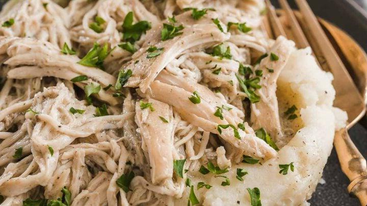 Pollo Cremoso in Pentola a Cottura Lenta 9 Piatto grigio con pollo sminuzzato su purè di patate.