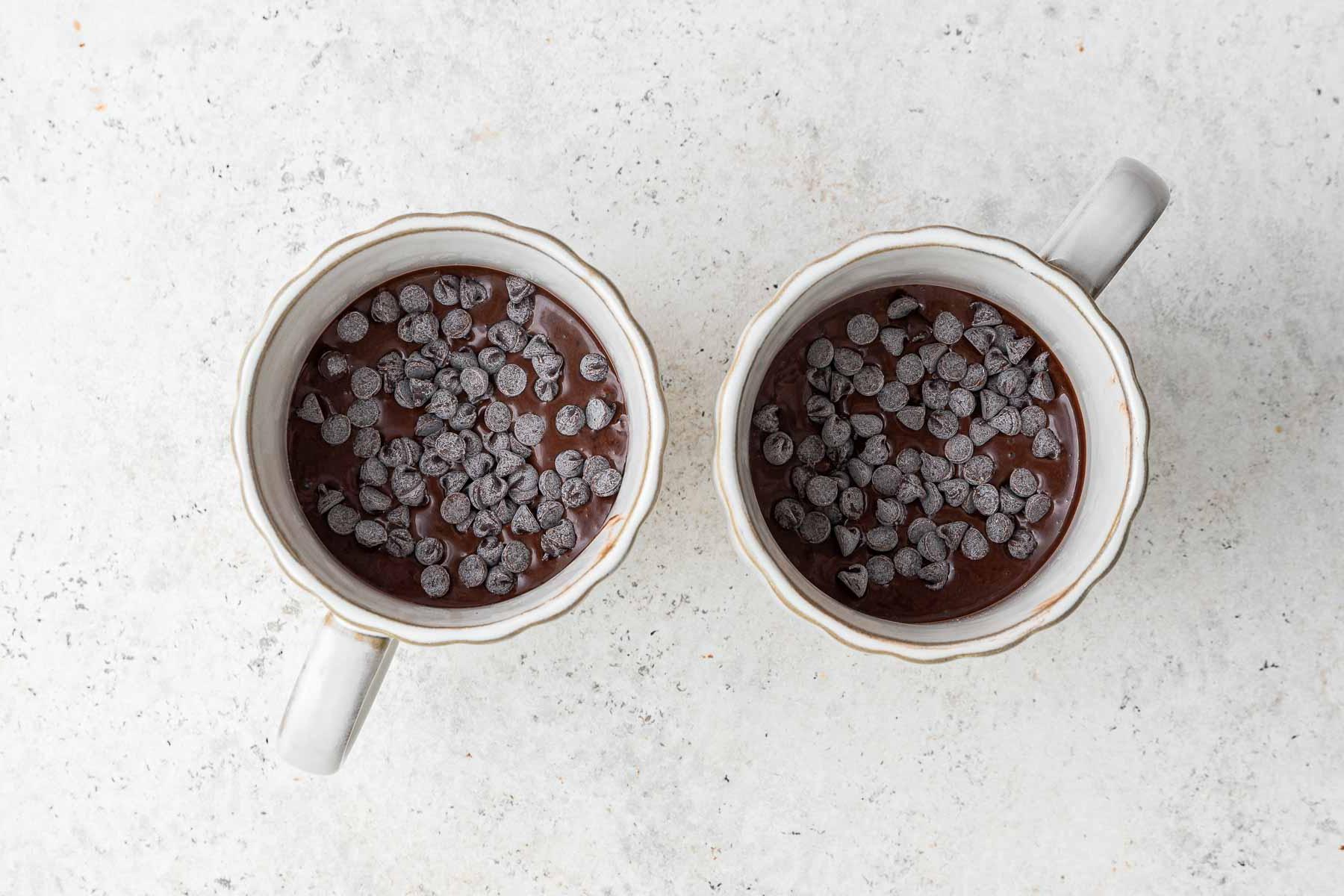 Ricetta Torta al Cioccolato in Tazza 9 Gocce di cioccolato sopra una torta al cioccolato in tazza, prima della cottura nel microonde.
