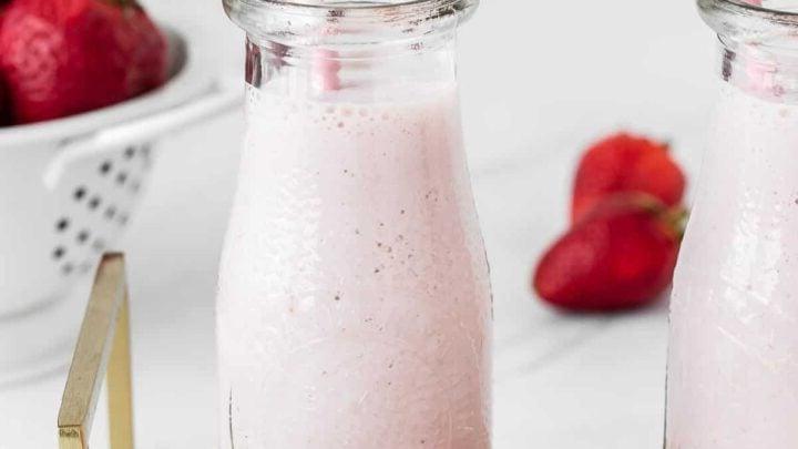 Latte alle fragole in un bicchiere con una cannuccia.
