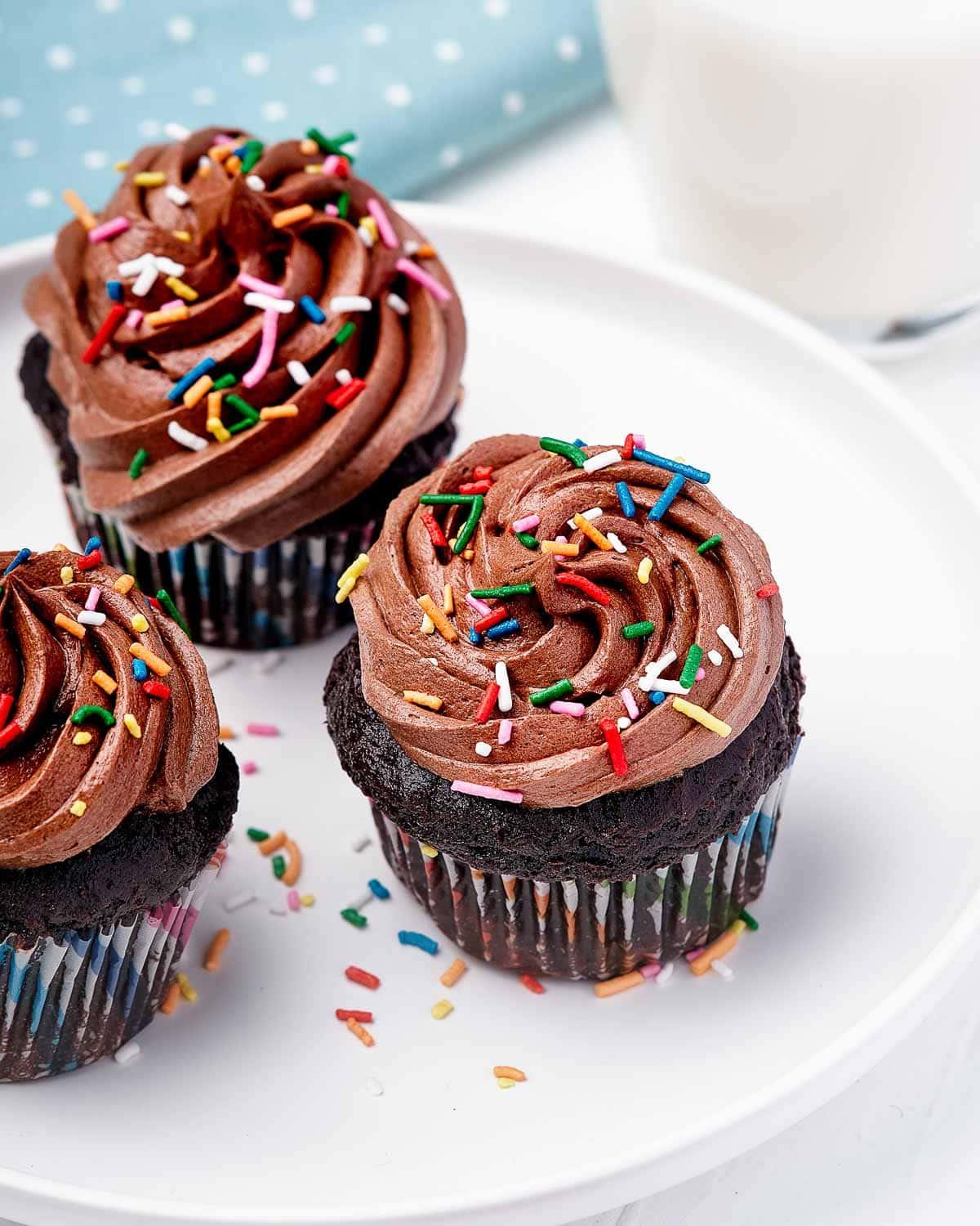 Piatto di cupcake con glassa al cioccolato e zuccherini.